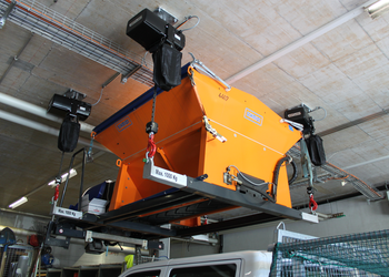 Electric chain hoists lift salt spreading barrel over people