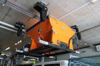 Electric chain hoists lift salt spreading barrel over people