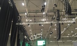 Electric chain hoists carry loudspeaker towers onto indoor stage