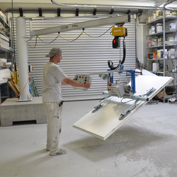 A wooden panel is lifted, turned and moved by means of a vacuum lifter
