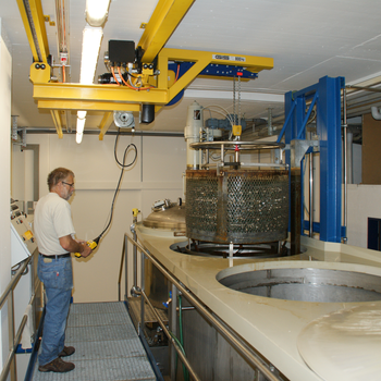 Crane system lifts metal container out of basin