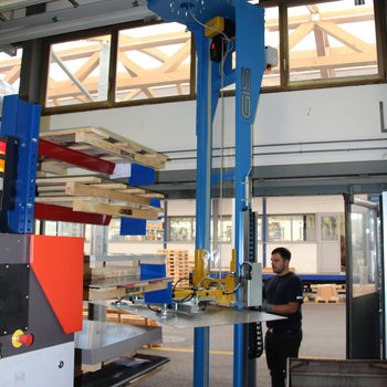 A sheet metal plate is lifted out of the rack with the crane system
