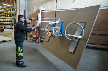 A large wooden panel is lifted by the forklift, tilted by 90° and moved to the vertical saw for cutting to size