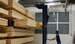 Shelf storage operation unit with lifting fork Wooden beams are lifted into the rack with a crane system